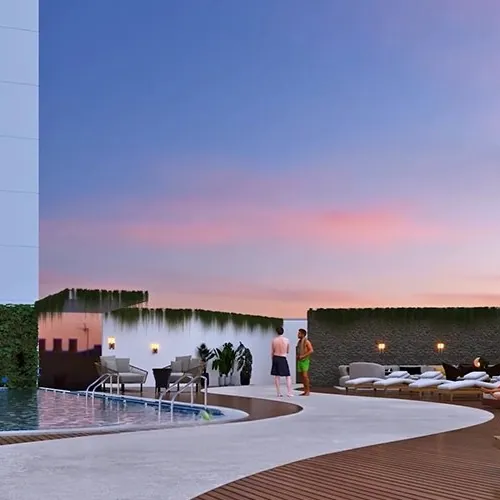 A rooftop pool with loungers at dusk at Aparna Sarovar Towers